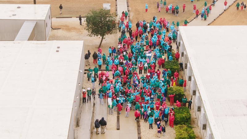 Personas detenidas en el Centro Residencial Familiar del Sur de Texas agitan carteles durante...