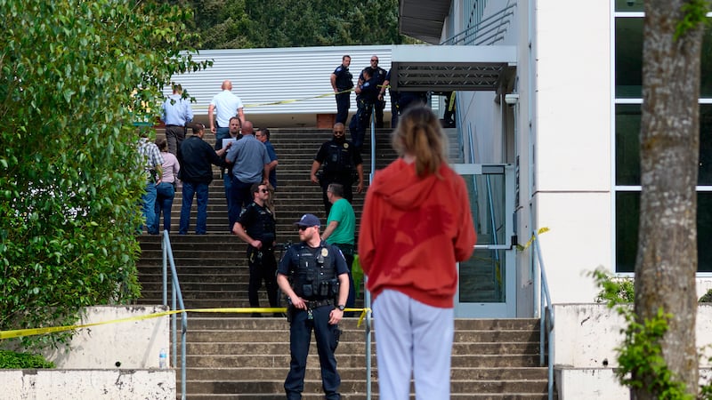 Un estudiante observa a agentes de la Policía de Tacoma luego de que varias personas...